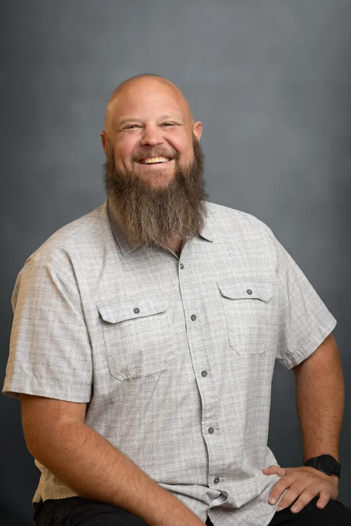 Smiling man with a beard in gray shirt.