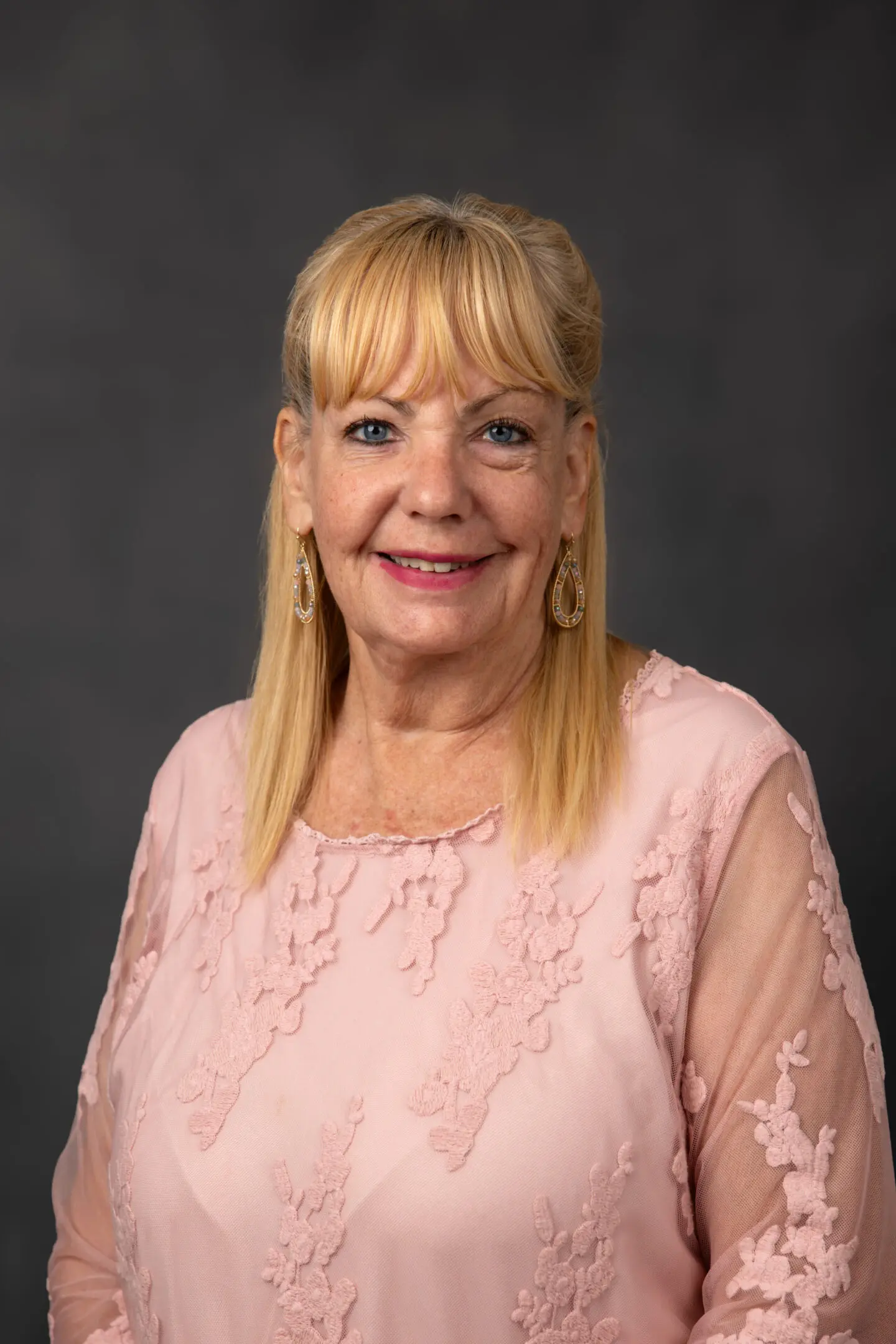 Portrait of a smiling elderly woman in a pink blouse.