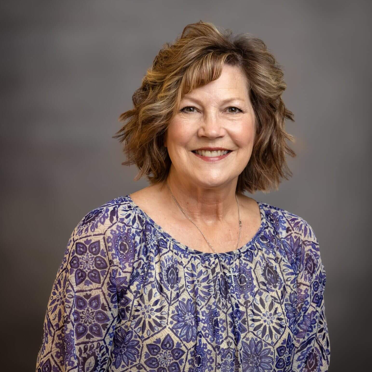 Smiling woman in purple patterned blouse