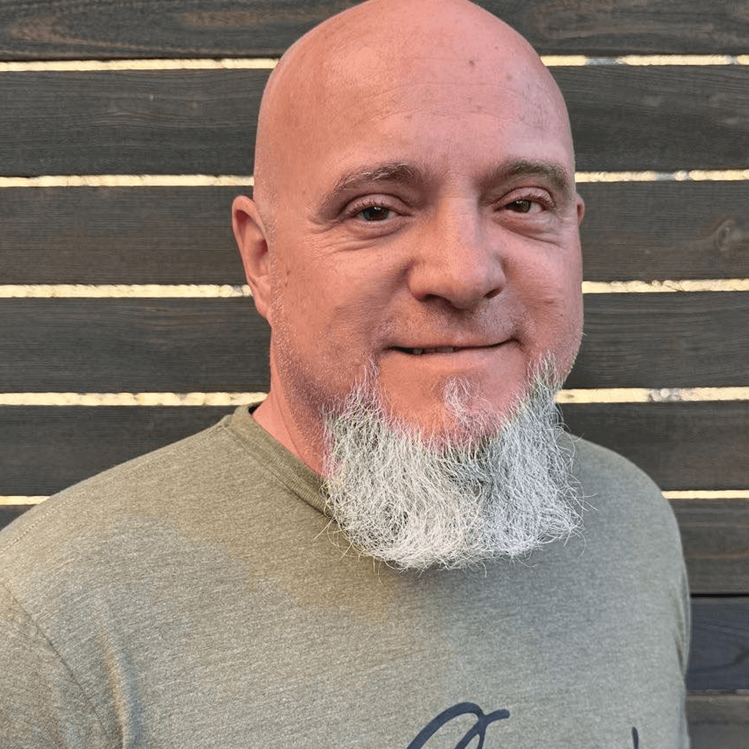Man with a gray beard wearing a green T-shirt.